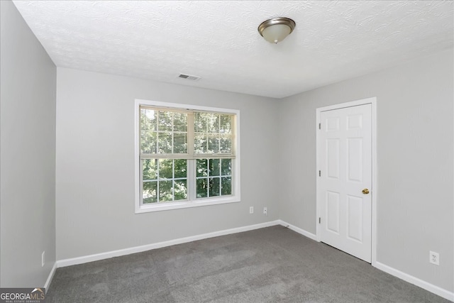 carpeted empty room featuring a textured ceiling