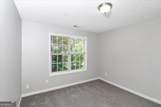 unfurnished room featuring a textured ceiling and dark carpet