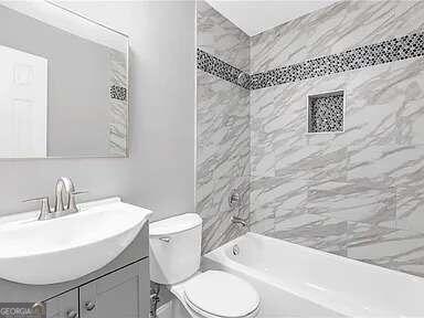 full bathroom featuring toilet, tiled shower / bath combo, and vanity