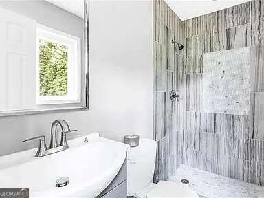 bathroom featuring vanity, toilet, and tiled shower