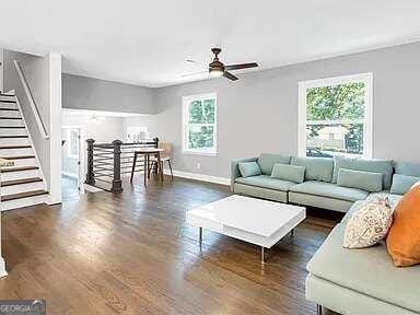 living room featuring dark wood-type flooring and ceiling fan