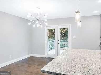 unfurnished dining area featuring french doors, a notable chandelier, and dark hardwood / wood-style floors