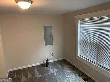 laundry area featuring dark carpet and electric panel