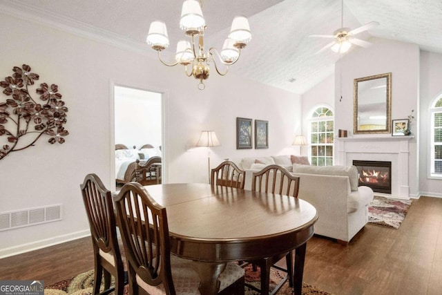 dining room featuring lofted ceiling, dark wood-type flooring, ornamental molding, a textured ceiling, and ceiling fan with notable chandelier