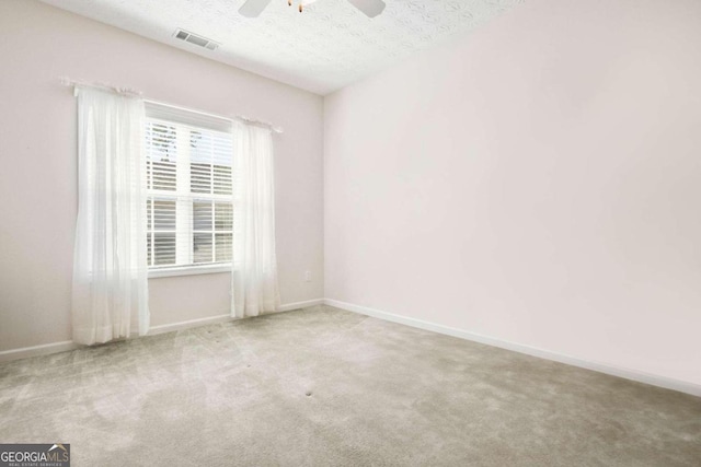 empty room featuring a textured ceiling, carpet, and ceiling fan