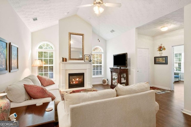 living room featuring dark wood-type flooring, a textured ceiling, high vaulted ceiling, and ceiling fan