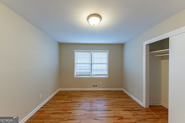 unfurnished bedroom featuring light hardwood / wood-style flooring and a closet