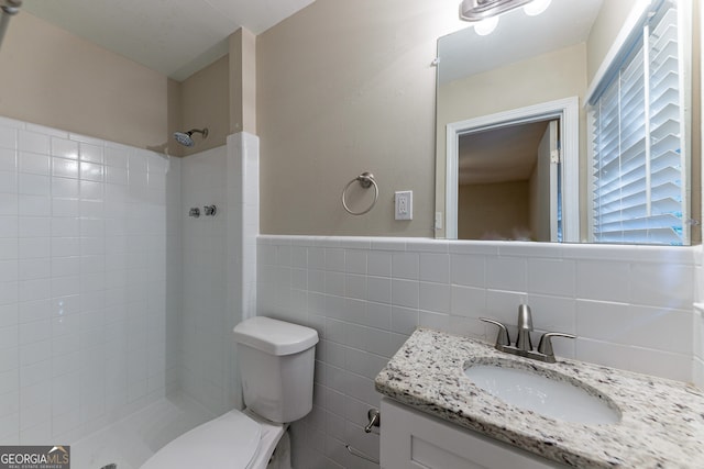 bathroom with tile walls, vanity, tiled shower, and toilet