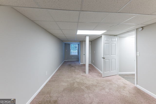 basement featuring a paneled ceiling and light colored carpet