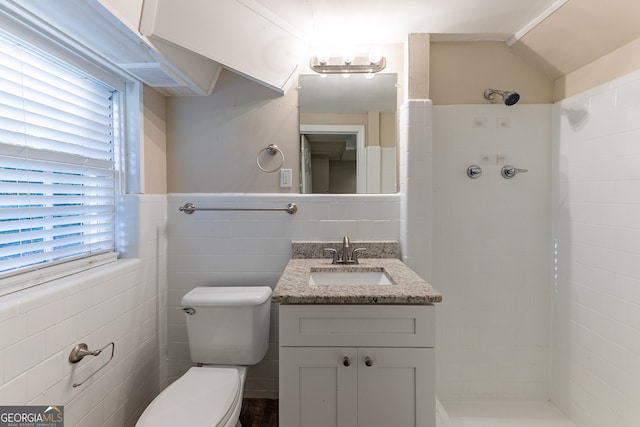 bathroom with vanity, toilet, a healthy amount of sunlight, and a tile shower