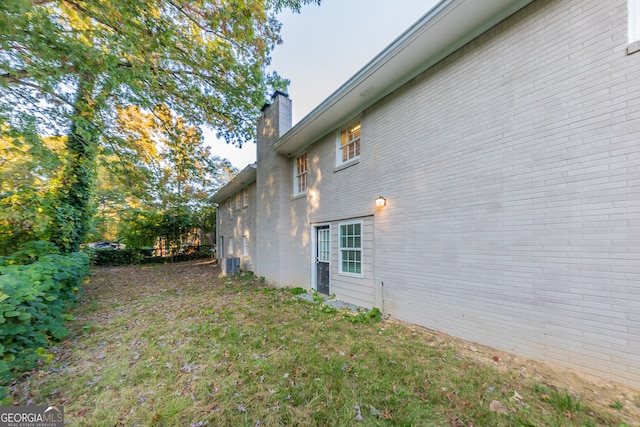 view of side of home featuring cooling unit and a lawn