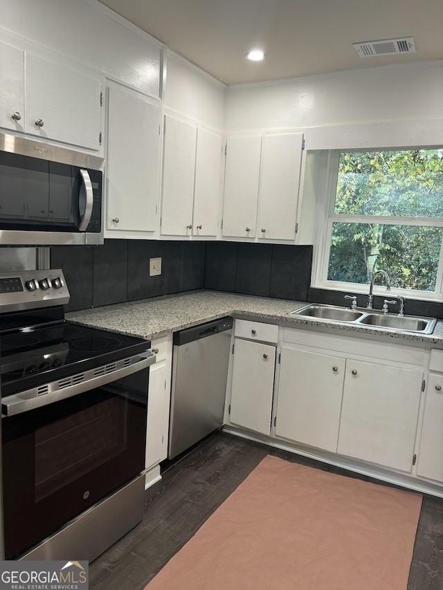 kitchen with white cabinets, appliances with stainless steel finishes, decorative backsplash, and sink