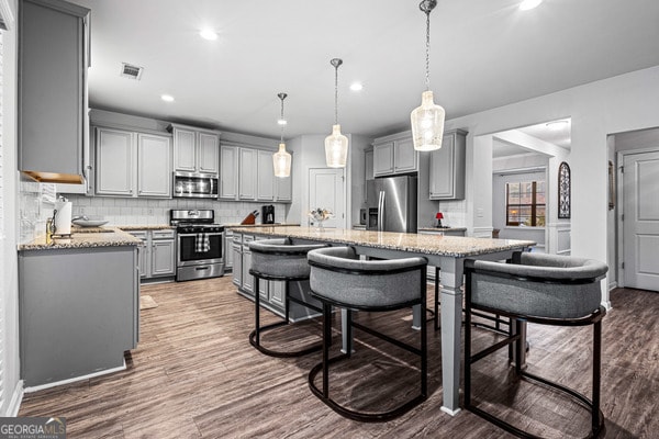 kitchen featuring gray cabinets, hanging light fixtures, hardwood / wood-style flooring, and stainless steel appliances