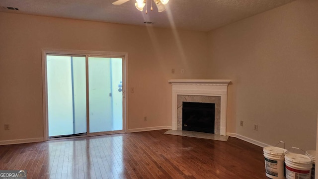 unfurnished living room with a textured ceiling, a fireplace, dark hardwood / wood-style floors, and ceiling fan