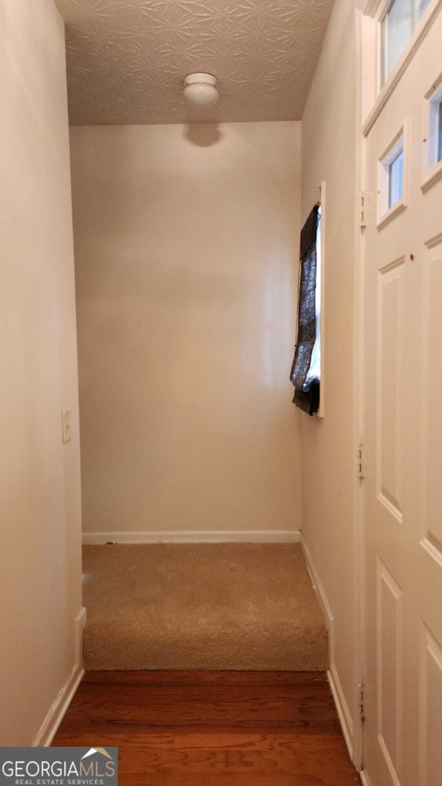 hall with hardwood / wood-style flooring and a textured ceiling