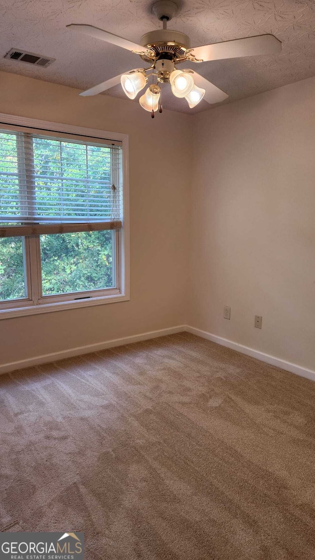 empty room with a textured ceiling, carpet flooring, and ceiling fan