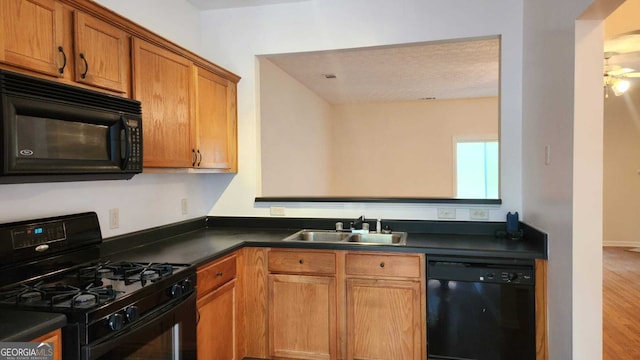 kitchen with hardwood / wood-style floors, sink, black appliances, and a textured ceiling