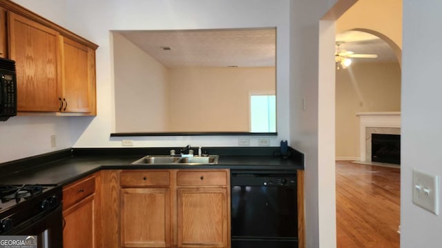 kitchen featuring light hardwood / wood-style flooring, sink, black appliances, a fireplace, and ceiling fan