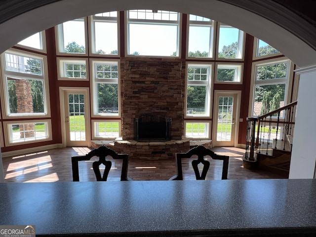 living room with a towering ceiling, wood-type flooring, and a fireplace