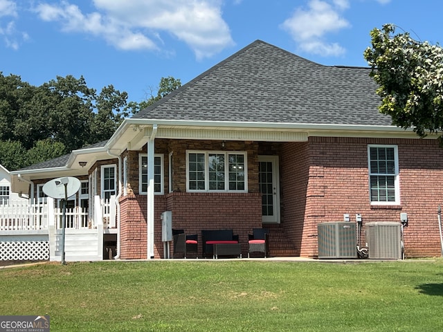 rear view of property with a yard and central AC