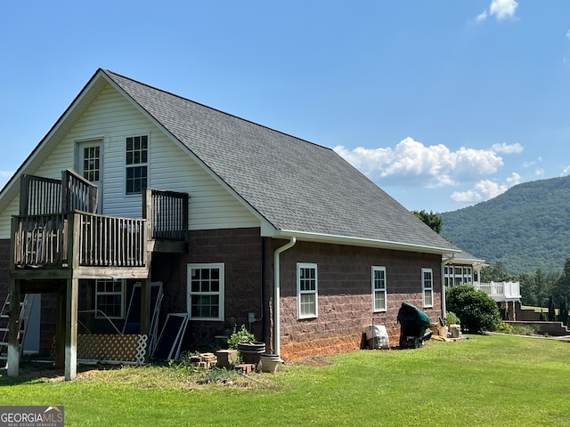 rear view of house with a balcony, a yard, and a mountain view