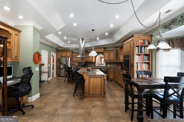 kitchen featuring appliances with stainless steel finishes, island range hood, hanging light fixtures, a breakfast bar area, and a center island with sink