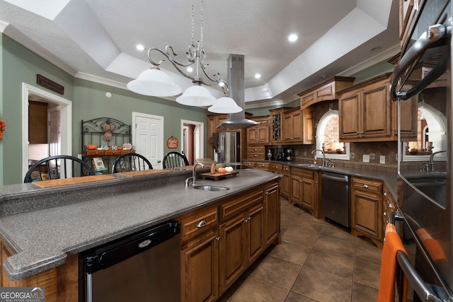 kitchen with a center island with sink, appliances with stainless steel finishes, a chandelier, a tray ceiling, and sink