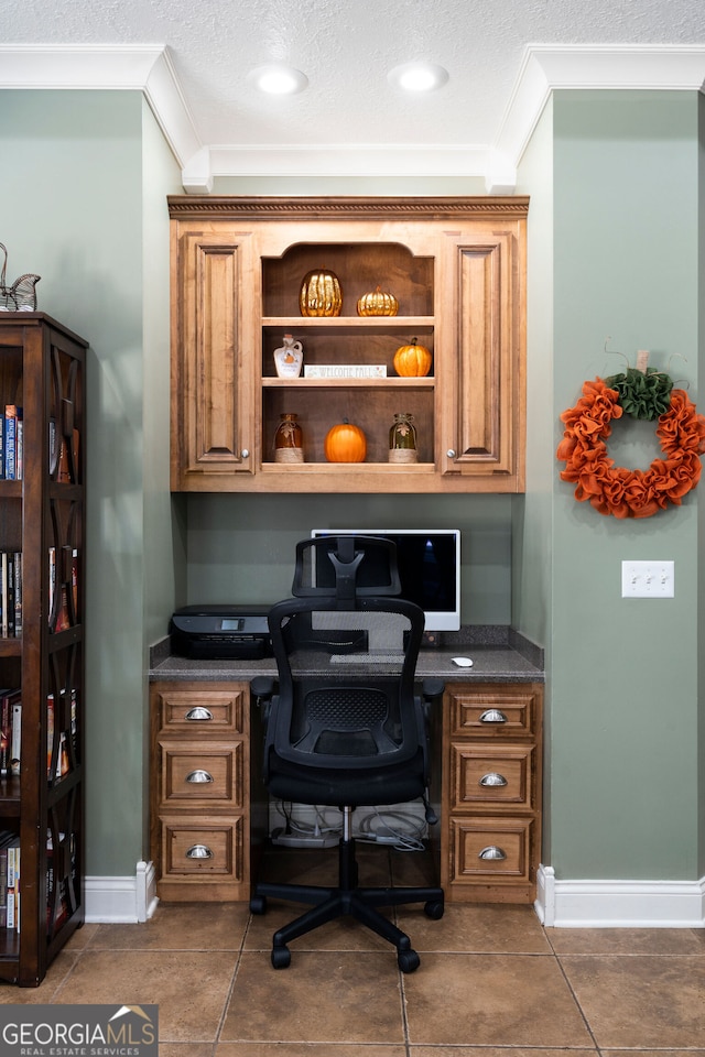 office area with ornamental molding, built in desk, a textured ceiling, and dark tile patterned flooring