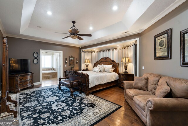 bedroom featuring connected bathroom, wood-type flooring, a tray ceiling, crown molding, and ceiling fan