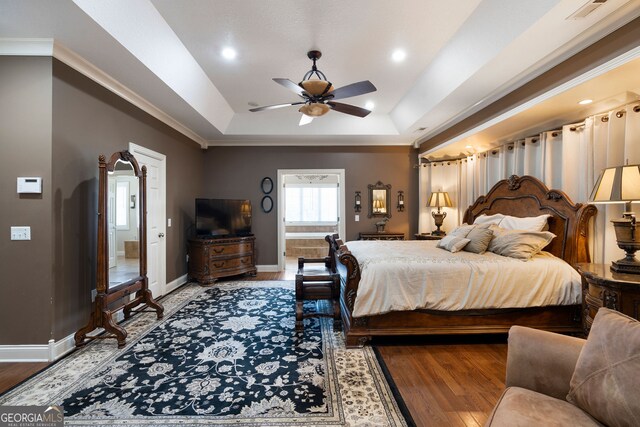 bedroom featuring ornamental molding, hardwood / wood-style flooring, a tray ceiling, and ceiling fan