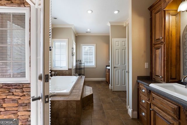 bathroom featuring vanity, a relaxing tiled tub, ornamental molding, and tile patterned flooring