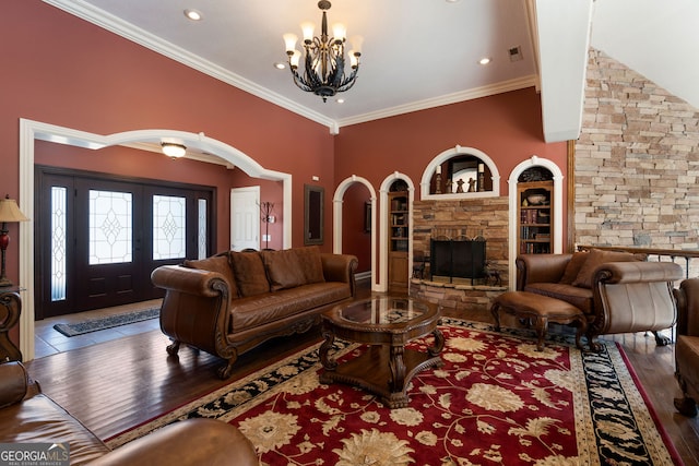 living room with hardwood / wood-style floors, an inviting chandelier, a fireplace, built in shelves, and crown molding