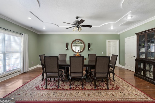 dining space featuring dark wood-type flooring, crown molding, a textured ceiling, and ceiling fan