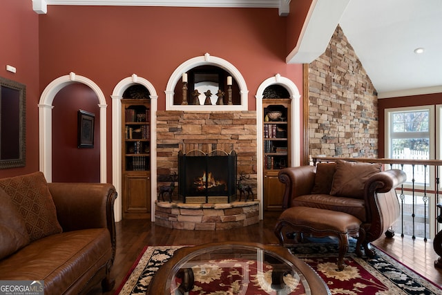 living room with ornamental molding, a stone fireplace, high vaulted ceiling, and dark hardwood / wood-style flooring