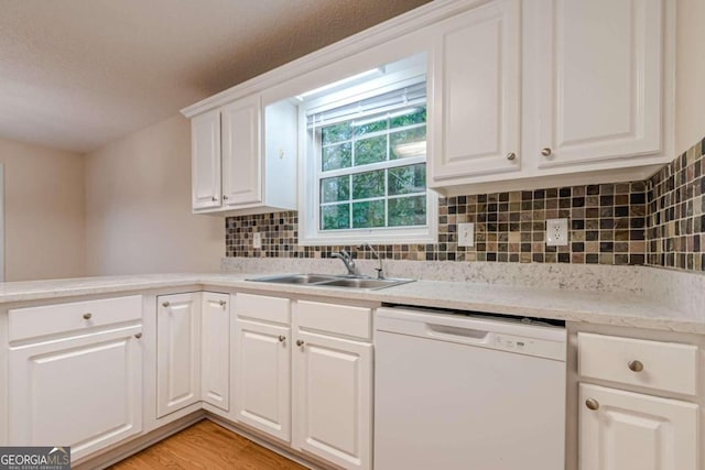 kitchen featuring white dishwasher, sink, light wood-type flooring, white cabinetry, and tasteful backsplash