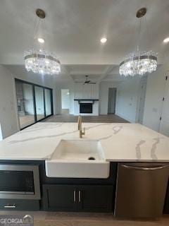 kitchen featuring stainless steel microwave, hanging light fixtures, a sink, and a fireplace