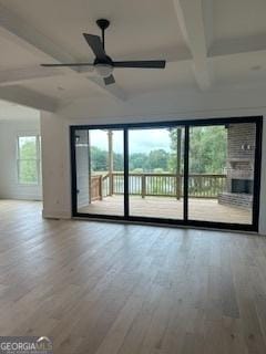 spare room with a healthy amount of sunlight, light wood finished floors, a ceiling fan, and beam ceiling