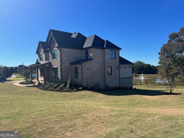 view of side of property with a water view, brick siding, and a yard