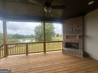 deck featuring ceiling fan and a brick fireplace