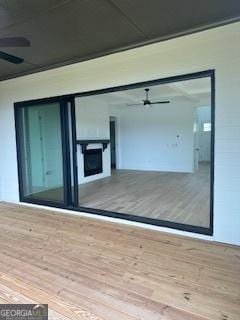 exterior space with a fireplace, a ceiling fan, and wood finished floors