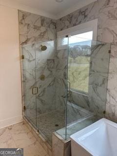 full bath with marble finish floor, a freestanding tub, a shower stall, and baseboards