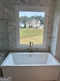 full bath with plenty of natural light, a freestanding tub, and a residential view