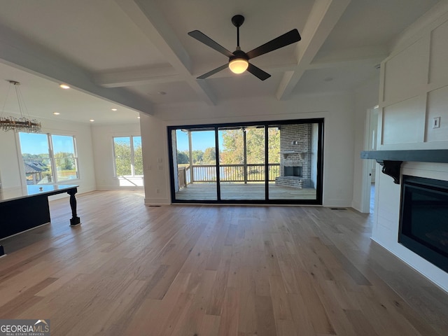 unfurnished living room with a glass covered fireplace, baseboards, beamed ceiling, and light wood finished floors