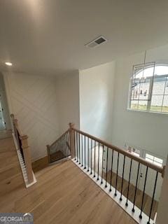 interior space featuring visible vents, an upstairs landing, and wood finished floors