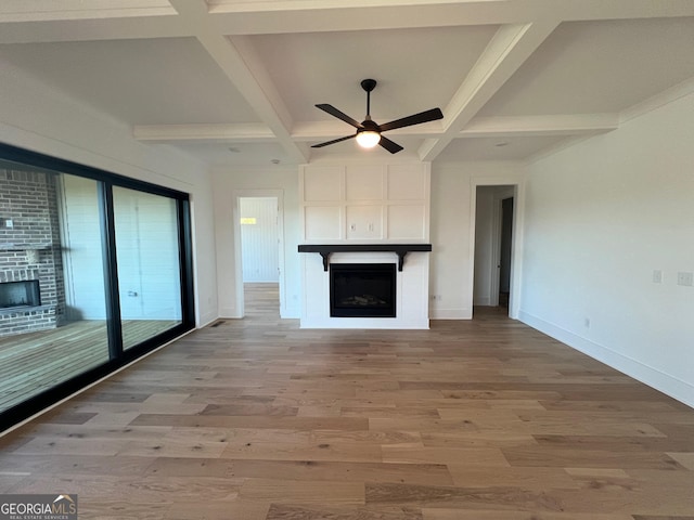 unfurnished living room featuring a fireplace, coffered ceiling, and light wood-style flooring