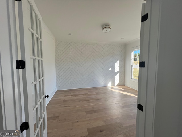 empty room with an accent wall, light wood-type flooring, and baseboards