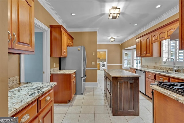 kitchen with crown molding, washer / clothes dryer, stainless steel appliances, and sink