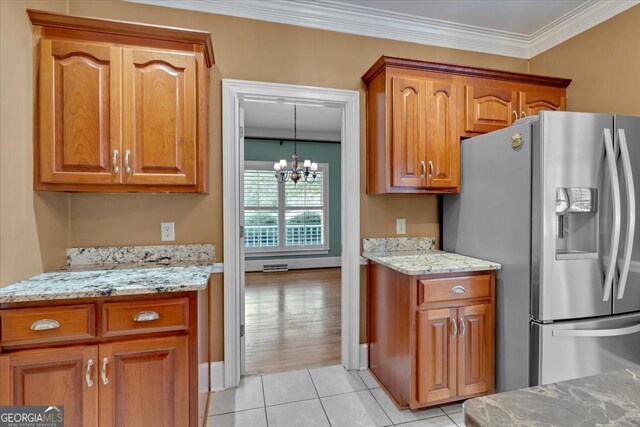 kitchen featuring stainless steel fridge, light tile patterned floors, light stone countertops, a chandelier, and ornamental molding