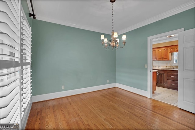 unfurnished dining area featuring ornamental molding, a chandelier, and light wood-type flooring