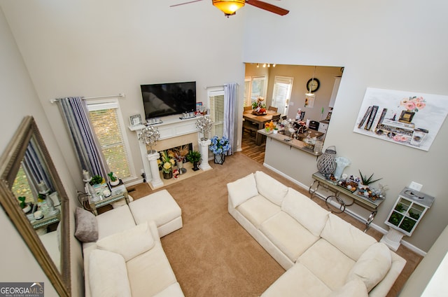 living room featuring carpet, ceiling fan, and a towering ceiling